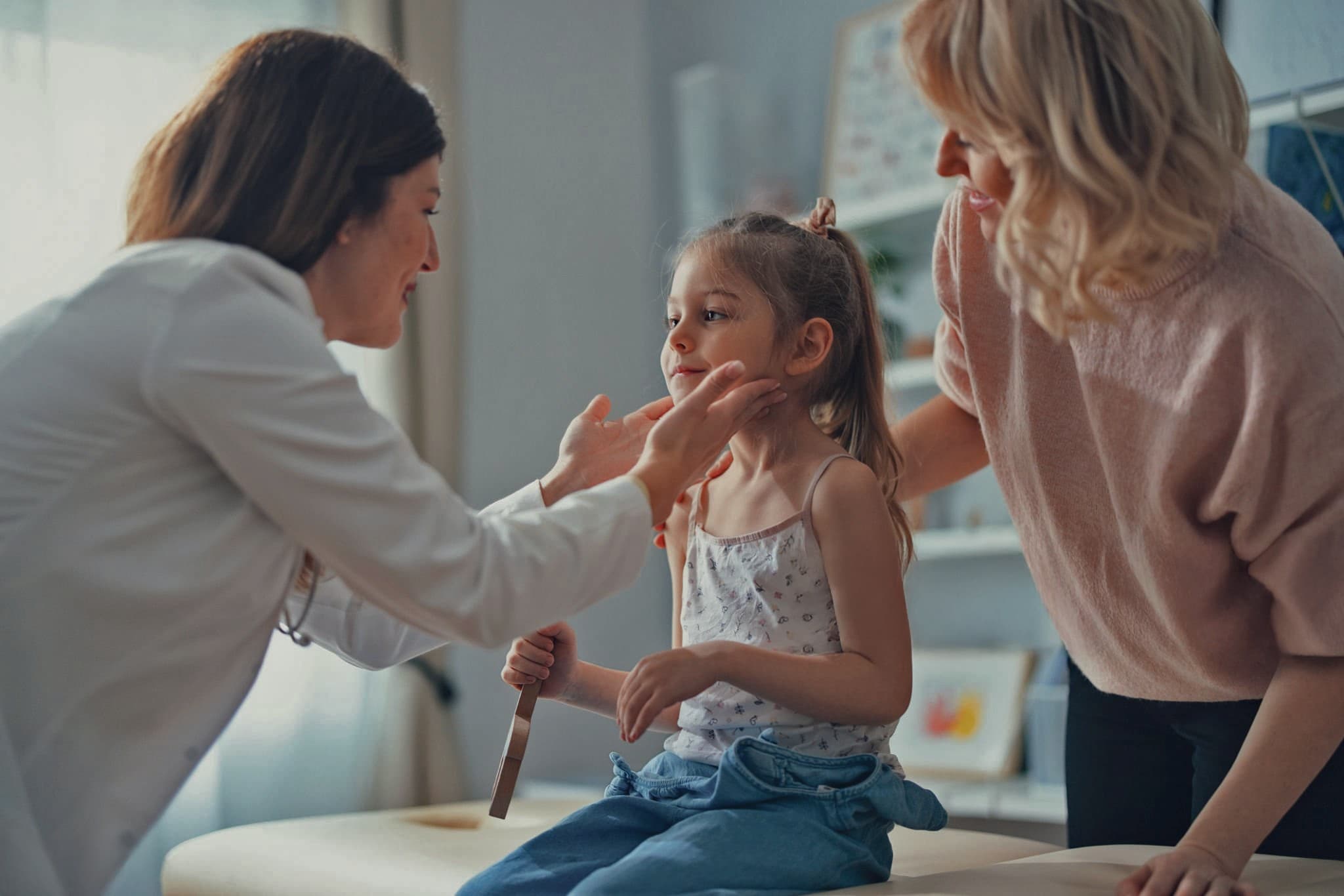 Pediatra examinando uma criança acompanhada da mãe