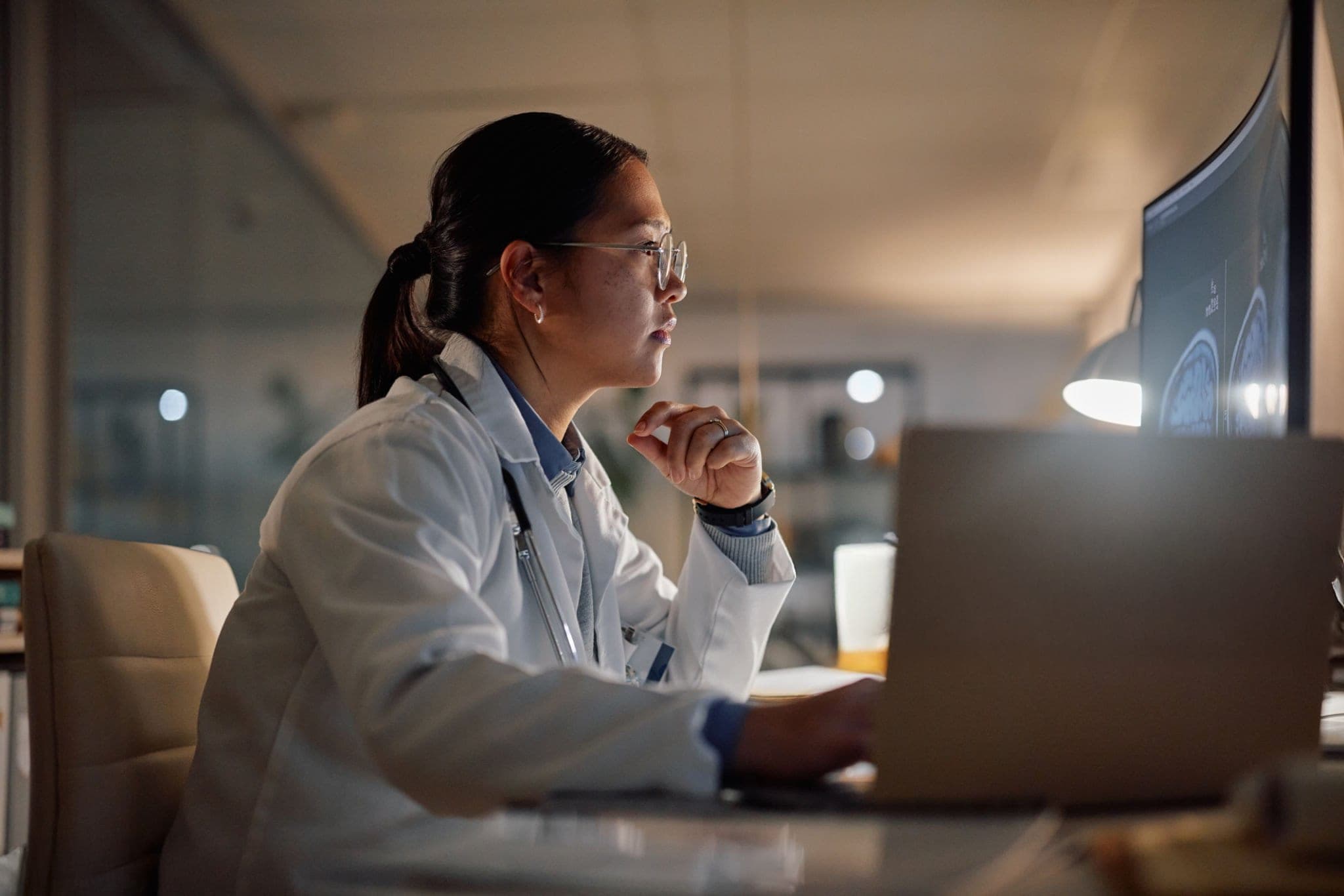 Médica analisando um exame de imagem na tela do consultório